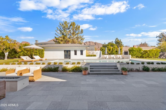 rear view of property with a fire pit and a patio