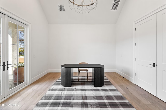 unfurnished room featuring light wood-type flooring, lofted ceiling, and a notable chandelier