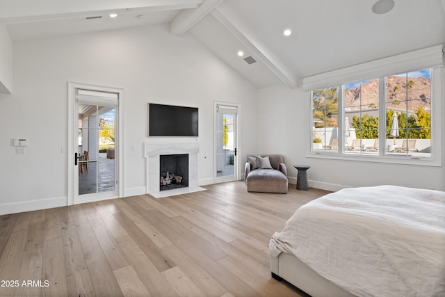 bedroom featuring access to exterior, a premium fireplace, beamed ceiling, and light hardwood / wood-style flooring