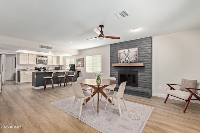 dining area featuring visible vents, a fireplace, light wood-type flooring, and baseboards