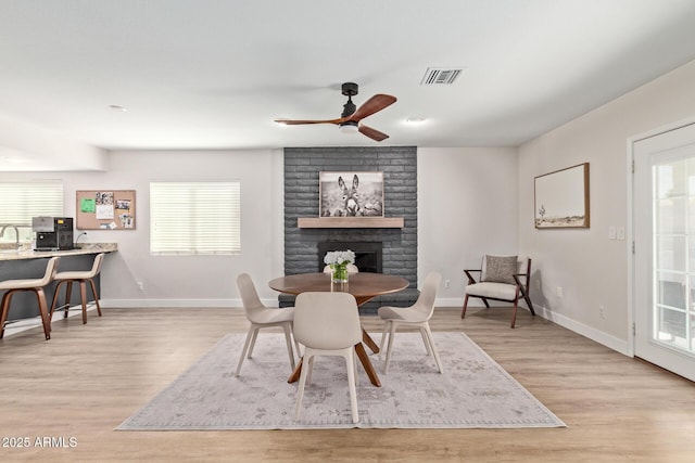 dining space featuring visible vents, a healthy amount of sunlight, a fireplace, and wood finished floors