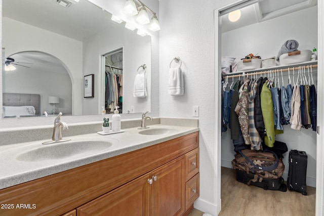 full bath featuring a sink, a spacious closet, wood finished floors, and double vanity