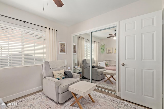 living area featuring ceiling fan, baseboards, and wood finished floors