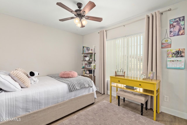 bedroom featuring baseboards, wood finished floors, and a ceiling fan