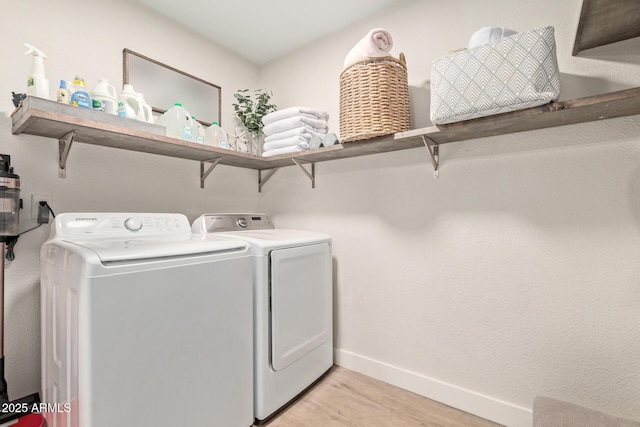 washroom featuring washer and dryer, laundry area, light wood-style flooring, and baseboards