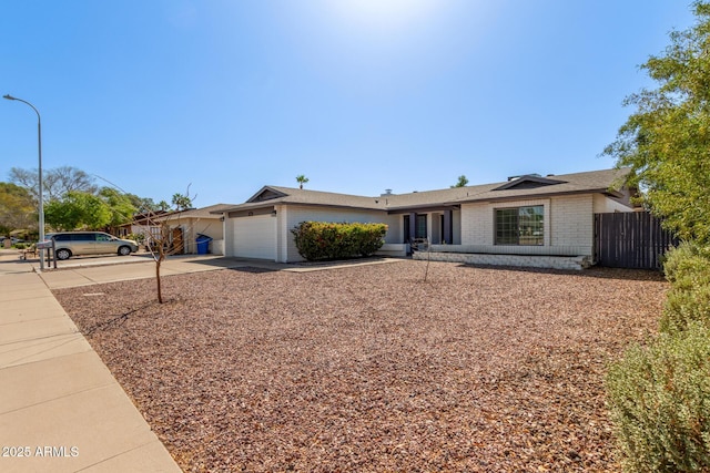 ranch-style house featuring brick siding, concrete driveway, a garage, and fence