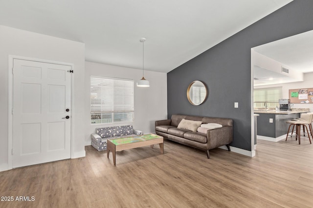 living room with lofted ceiling, light wood-style floors, visible vents, and baseboards