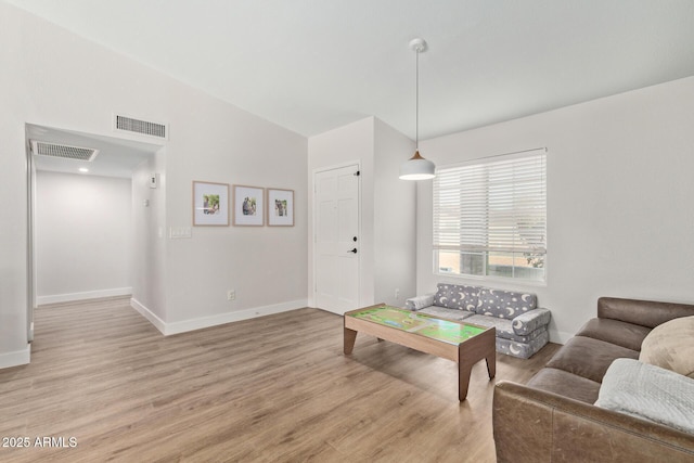 living room with baseboards, visible vents, and light wood-type flooring