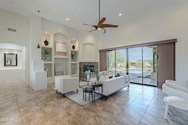 28423 N 139th St, Scottsdale, AZ 85262 - living room featuring a glass covered fireplace, a high ceiling, visible vents, a ceiling fan, and built in features