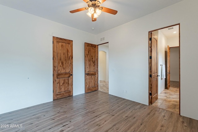 28423 N 139th St, Scottsdale, AZ 85262 - unfurnished bedroom featuring visible vents, arched walkways, wood finished floors, and ceiling fan