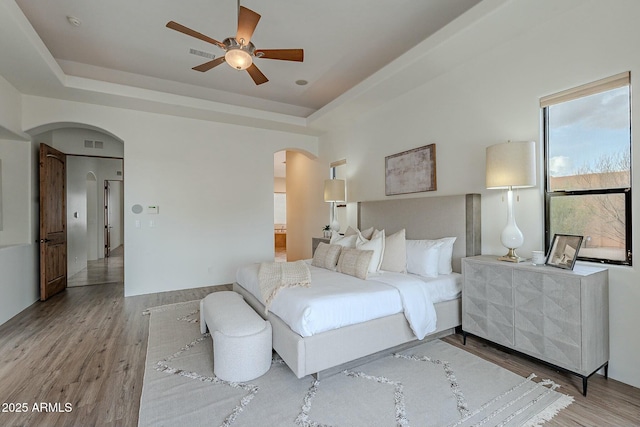 28423 N 139th St, Scottsdale, AZ 85262 - bedroom featuring a raised ceiling, arched walkways, ensuite bath, visible vents, and wood finished floors