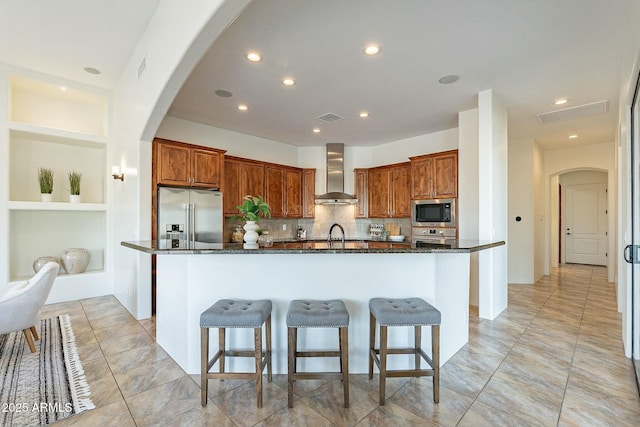 28423 N 139th St, Scottsdale, AZ 85262 - kitchen with stainless steel appliances, a center island with sink, arched walkways, visible vents, and wall chimney exhaust hood