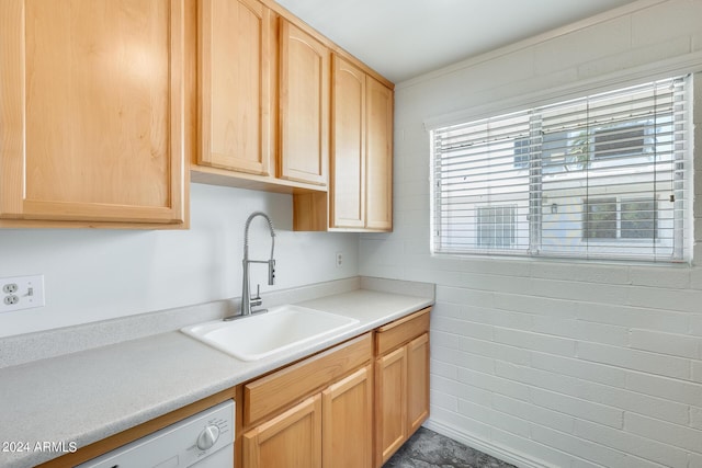 kitchen featuring white dishwasher, light countertops, a sink, and light brown cabinetry