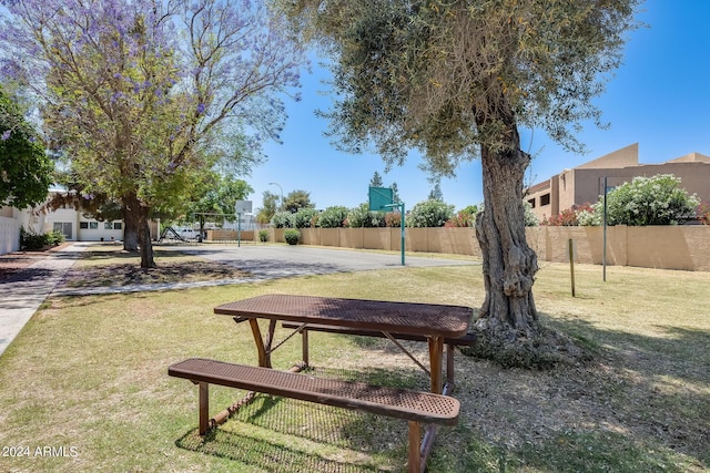 surrounding community featuring community basketball court, a lawn, and fence