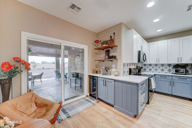 kitchen featuring beverage cooler, visible vents, decorative backsplash, light countertops, and appliances with stainless steel finishes