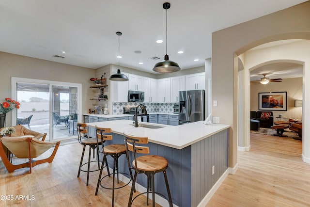 kitchen with visible vents, a breakfast bar, arched walkways, a sink, and appliances with stainless steel finishes