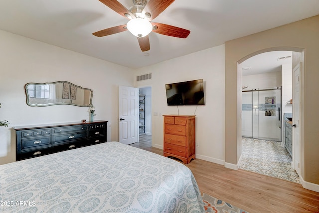 bedroom with arched walkways, visible vents, baseboards, and light wood-style floors