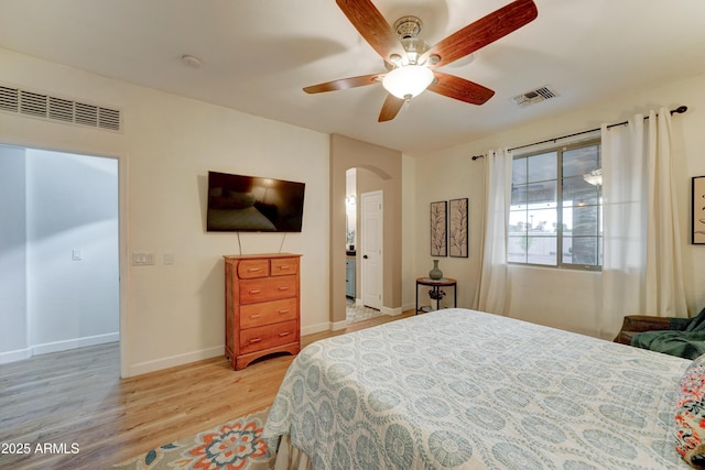 bedroom featuring arched walkways, visible vents, light wood finished floors, and baseboards