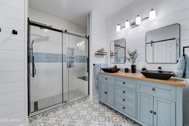 bathroom with double vanity, a shower stall, and a sink