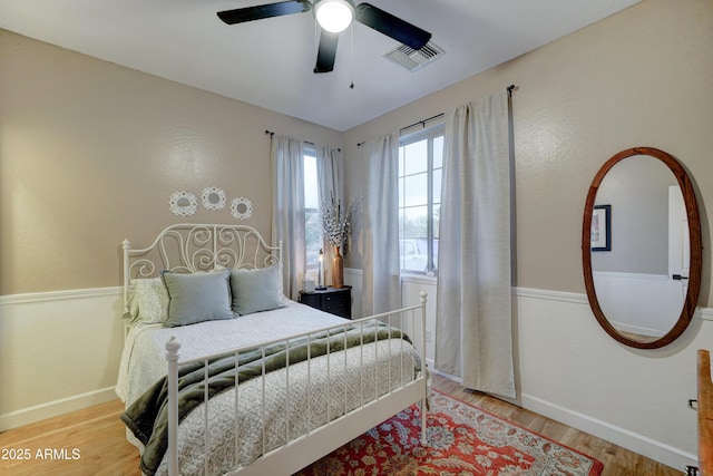 bedroom with visible vents, a ceiling fan, baseboards, and wood finished floors