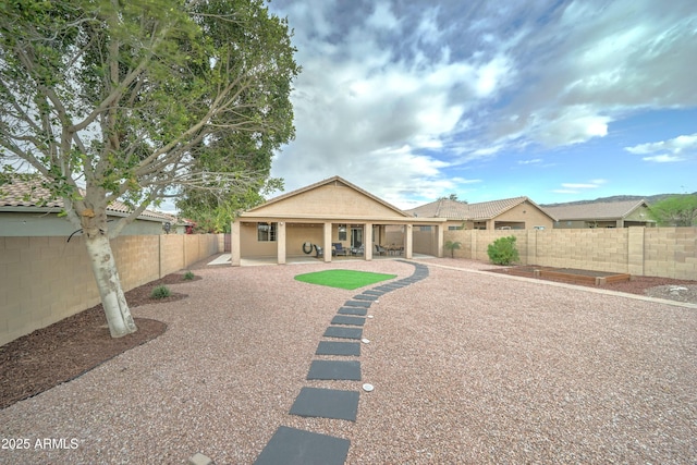 back of house with a fenced backyard, stucco siding, and a patio