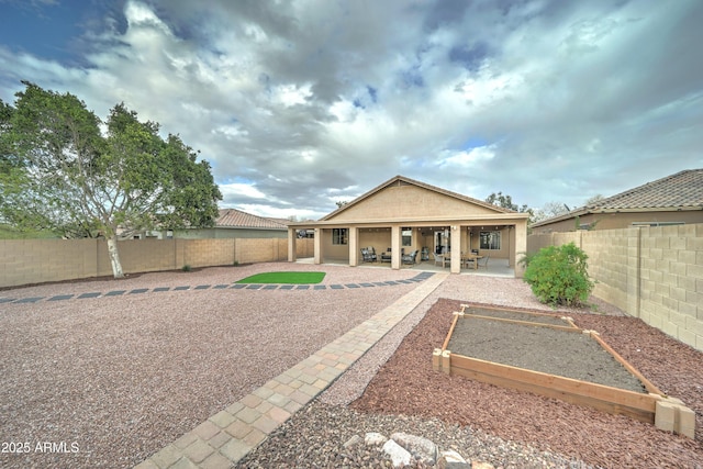 rear view of house featuring a garden, stucco siding, a patio, and a fenced backyard