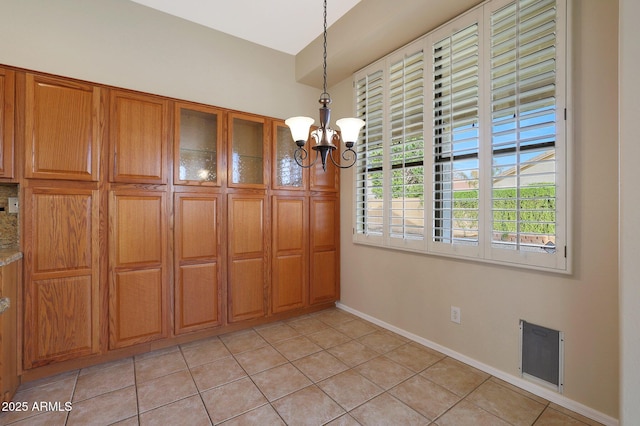 unfurnished dining area featuring light tile patterned flooring and a chandelier