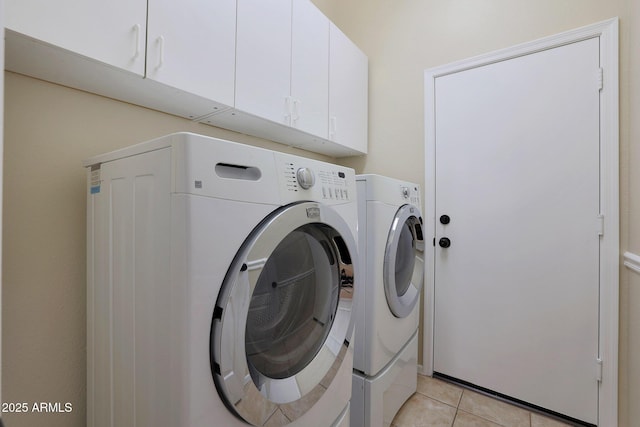 laundry room featuring cabinets, light tile patterned flooring, and washing machine and clothes dryer