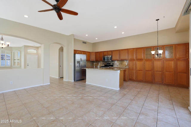 kitchen featuring ceiling fan with notable chandelier, stainless steel appliances, light stone counters, decorative backsplash, and decorative light fixtures