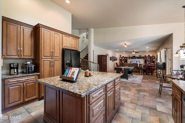 1922 E Everett Dr, Phoenix, AZ 85022 - kitchen with black fridge, ceiling fan, a kitchen island, light stone counters, and open floor plan