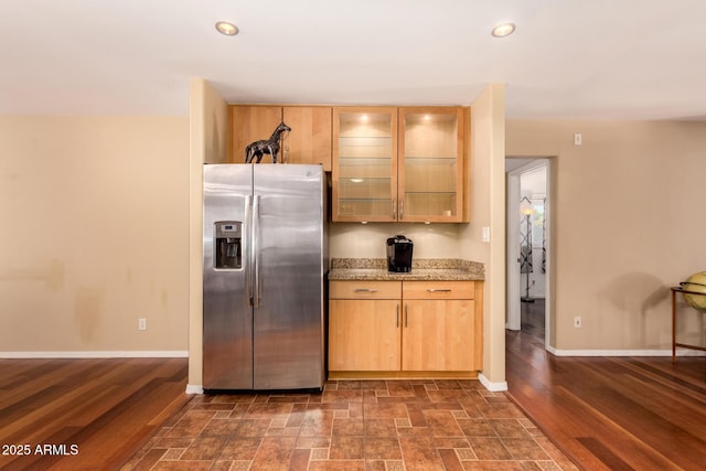 kitchen with stainless steel fridge with ice dispenser, light brown cabinets, dark hardwood / wood-style flooring, and light stone counters