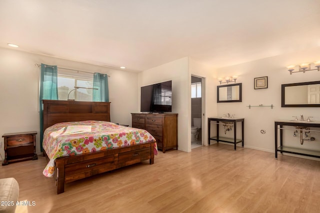 bedroom with ensuite bath and light hardwood / wood-style floors