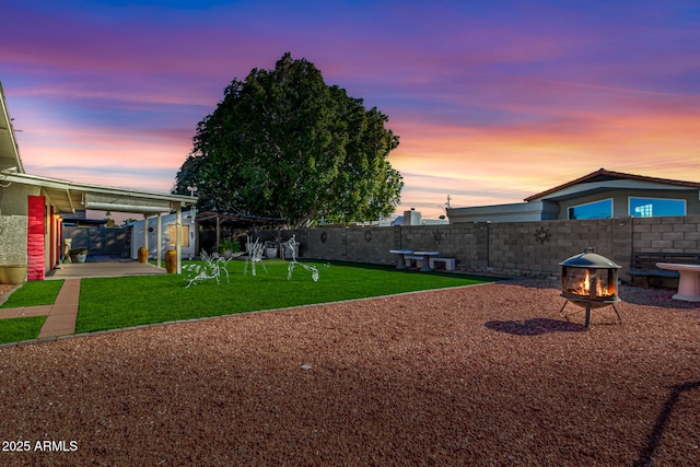 yard at dusk featuring an outdoor fire pit and a patio area