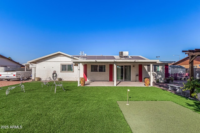 back of property featuring central AC unit, solar panels, a patio area, and a yard