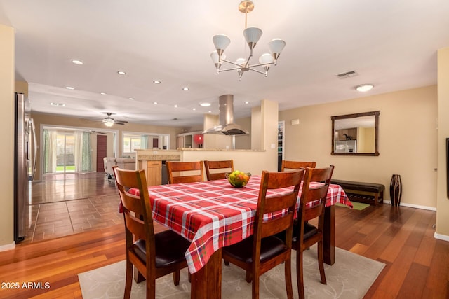 dining area featuring wood-type flooring and ceiling fan with notable chandelier