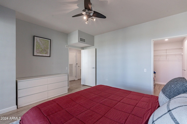 bedroom with light hardwood / wood-style floors, a walk in closet, a closet, and ceiling fan