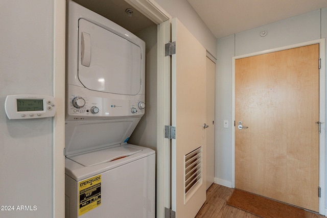 laundry room with stacked washer / drying machine and wood-type flooring