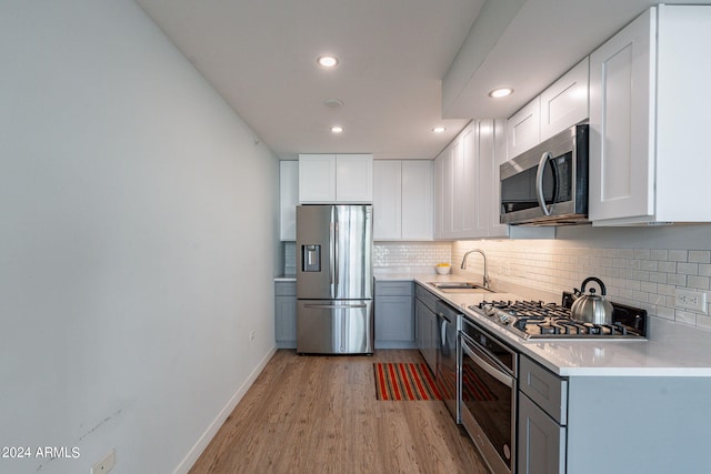 kitchen featuring decorative backsplash, white cabinetry, light hardwood / wood-style flooring, sink, and stainless steel appliances