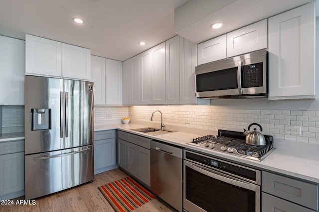 kitchen featuring white cabinetry, stainless steel appliances, sink, and light wood-type flooring