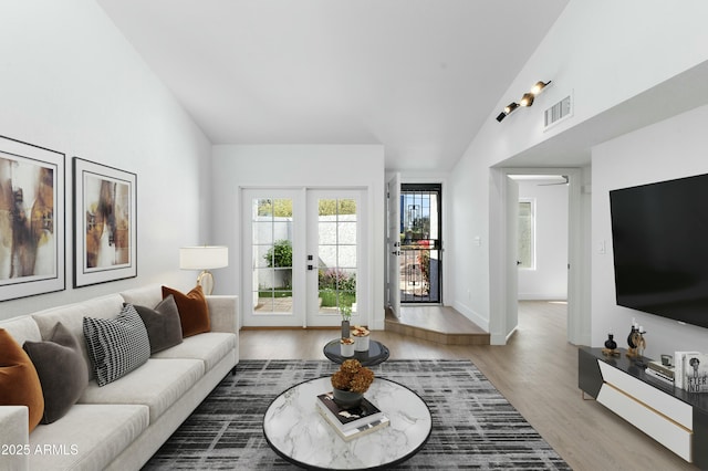 living room with lofted ceiling, hardwood / wood-style flooring, and french doors