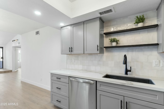 kitchen with sink, stainless steel dishwasher, gray cabinets, light stone countertops, and backsplash