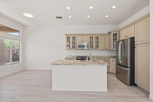 kitchen featuring a kitchen island with sink, stainless steel appliances, visible vents, and glass insert cabinets