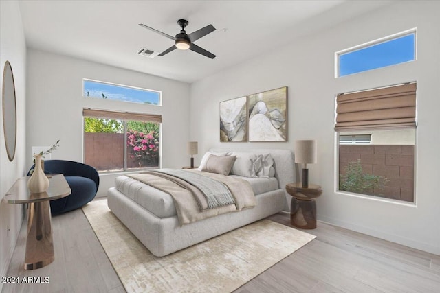 bedroom featuring light wood-type flooring, ceiling fan, visible vents, and baseboards