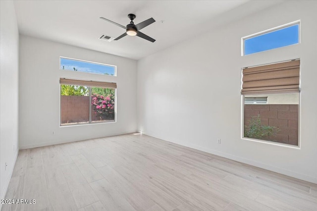 spare room featuring ceiling fan, light wood-type flooring, visible vents, and baseboards