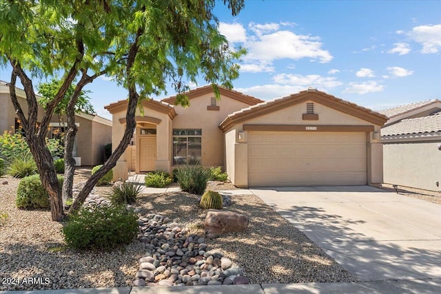 mediterranean / spanish home with a garage, a tiled roof, concrete driveway, and stucco siding