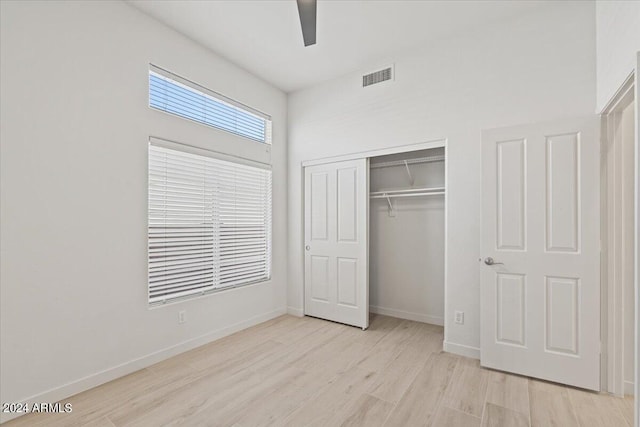 unfurnished bedroom with baseboards, visible vents, a ceiling fan, light wood-type flooring, and a closet