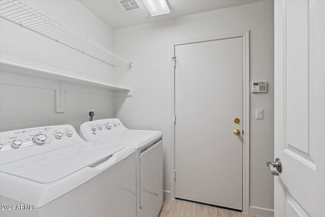 laundry room featuring laundry area, light wood-type flooring, washing machine and dryer, and visible vents