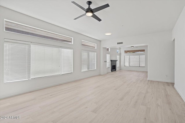 unfurnished living room featuring a fireplace, visible vents, light wood-style floors, ceiling fan, and baseboards