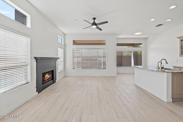 living area featuring a wealth of natural light, visible vents, a lit fireplace, and light wood finished floors