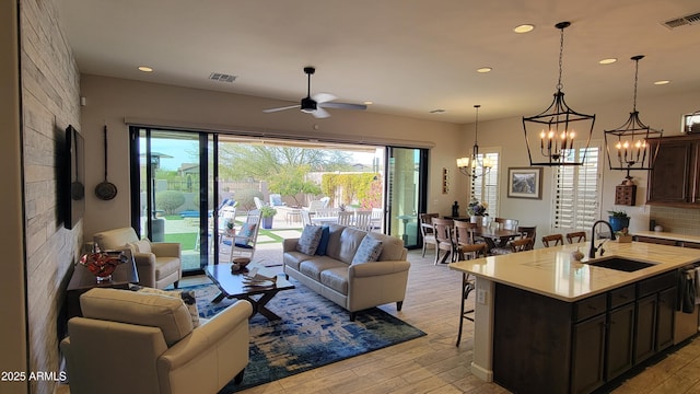 living area with light wood-style flooring, ceiling fan with notable chandelier, visible vents, and recessed lighting